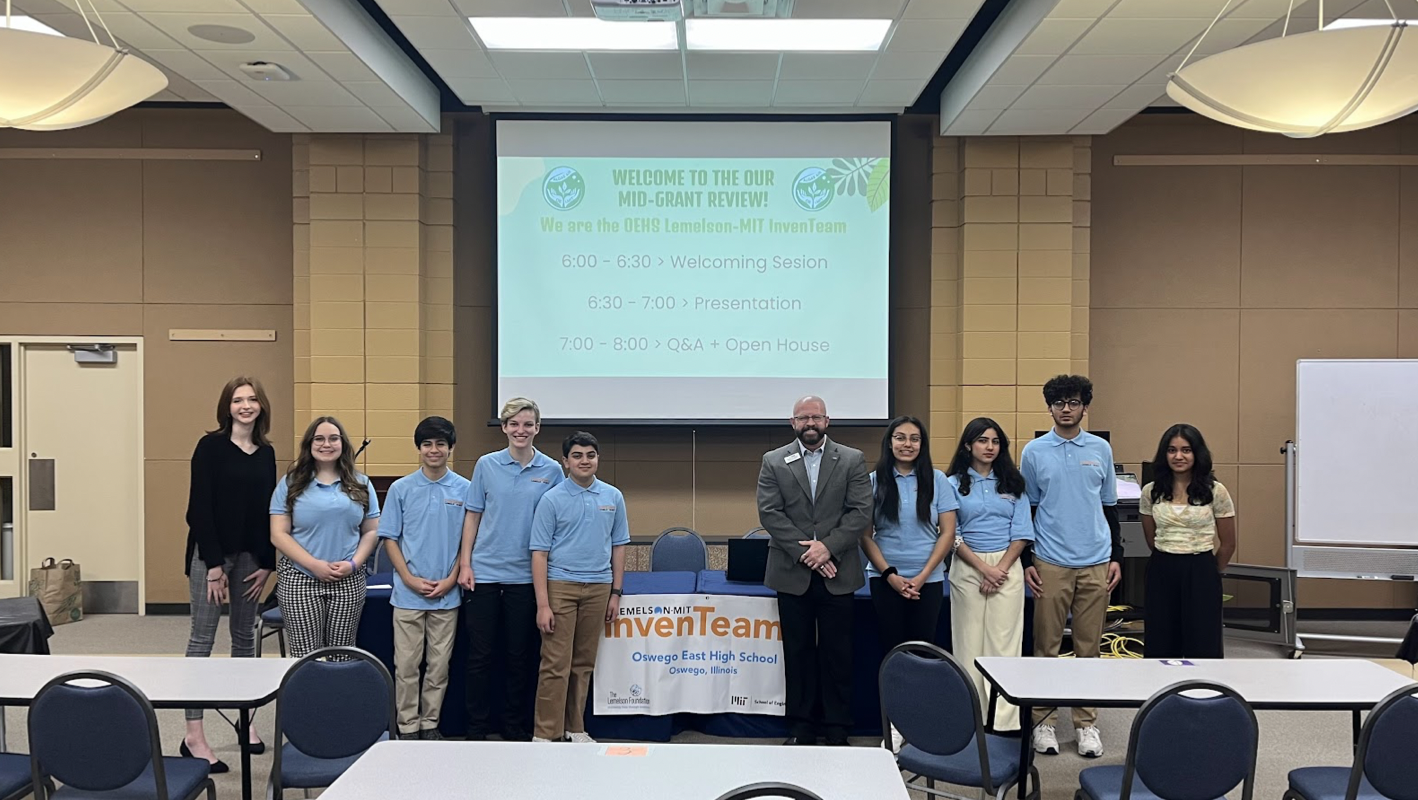 Our team standing with our school superintendent in front of our slideshow presentation