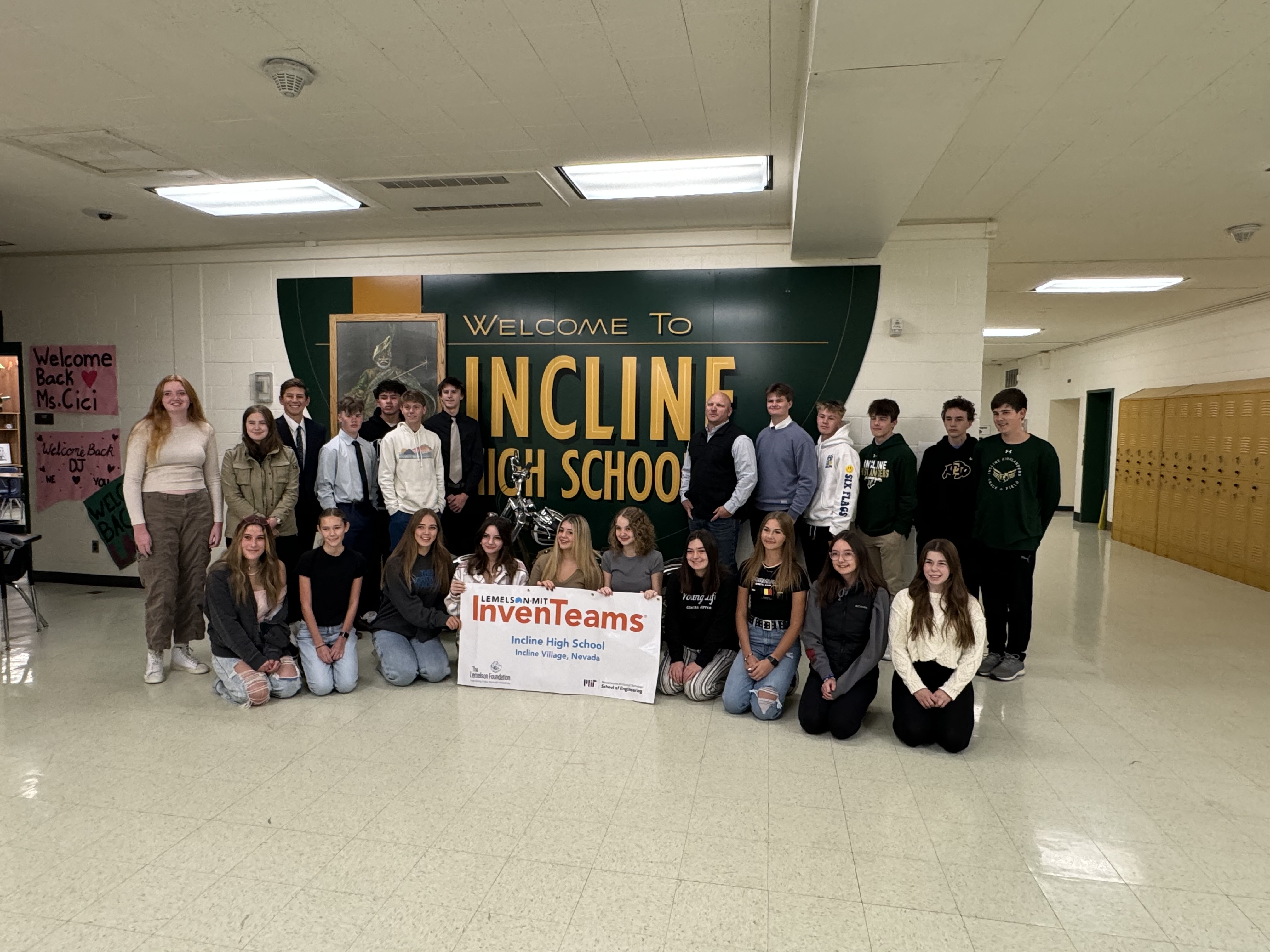 The Incline Village InvenTeam around a sign that says "Welcome to Incline High School". They are holding a poster with the Lemelson-MIT InvenTeams logo on it. 