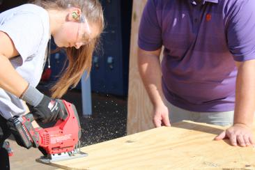 Student uses a jigsaw to cut wood. 