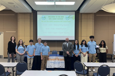 Our team standing with our school superintendent in front of our slideshow presentation